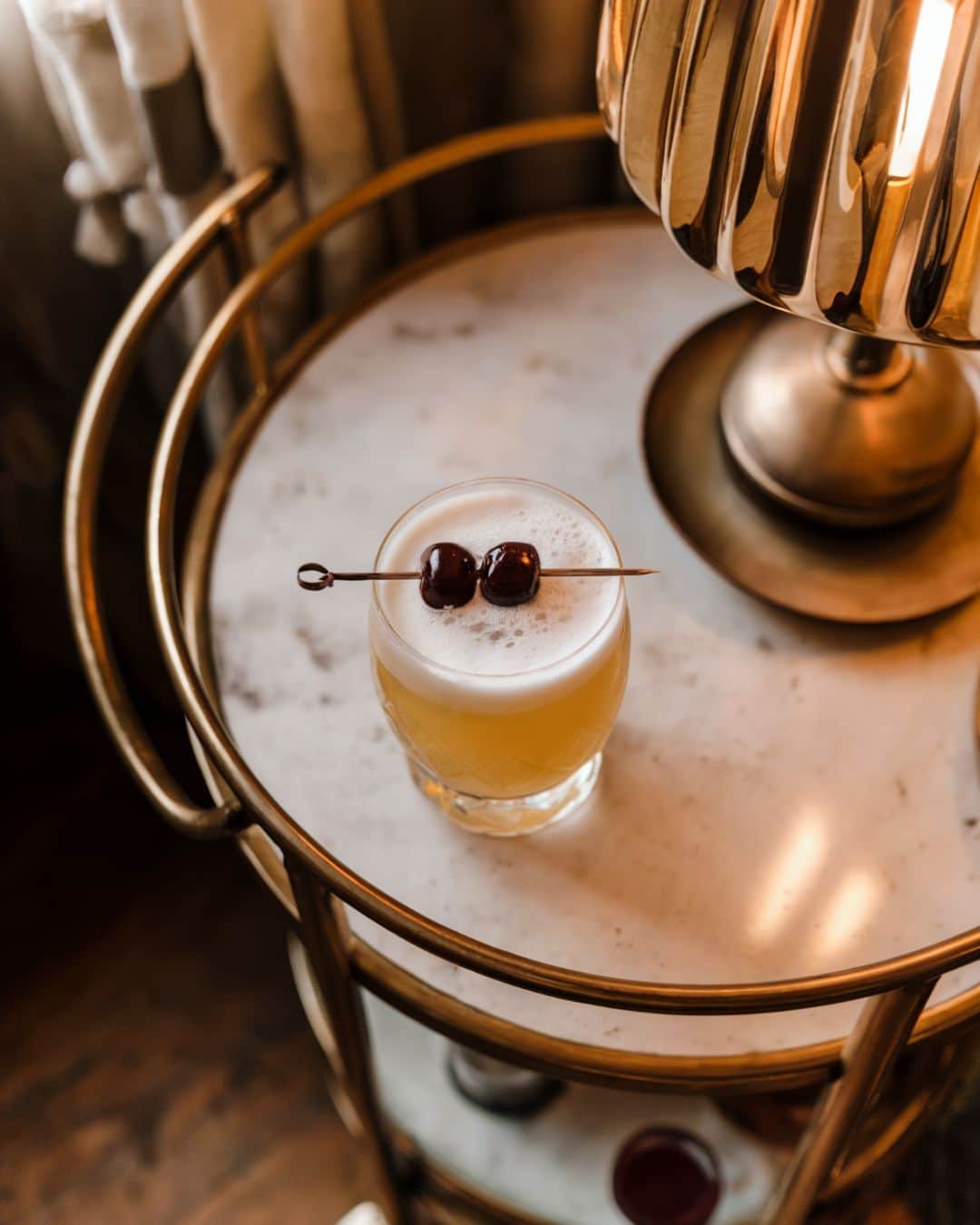 whiskey sour cocktail sitting on a bar cart