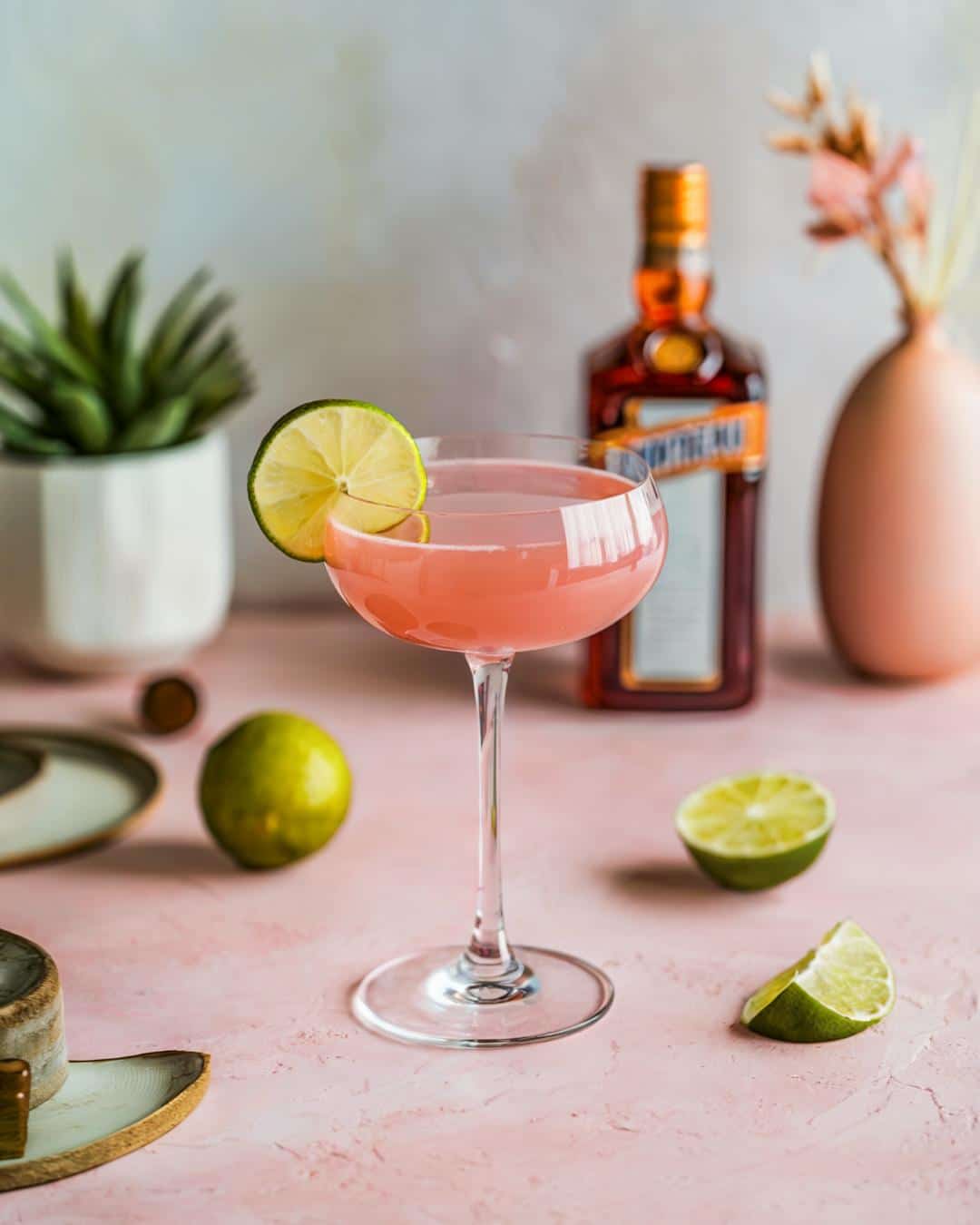 A chic pink Cosmopolitan cocktail with a lime garnish, perfect for those seeking a cosmopolitan cocktail recipe, vodka cocktail ideas, or 90s cocktails drink recipes.