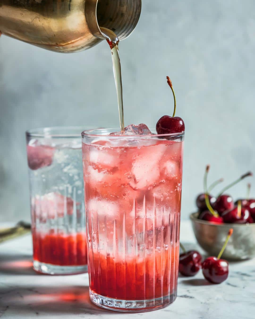 dirty shirley cocktail in a collins glass made with vodka, grenadine and sprite with a cherry on top