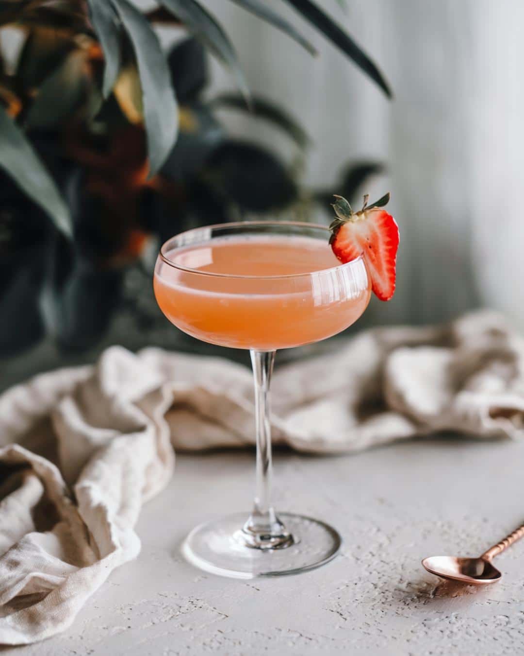 A freshly made strawberry margarita in a coupe glass with a strawberry garnish, ideal for pink alcoholic drinks for a party or a fresh strawberry margarita recipe.