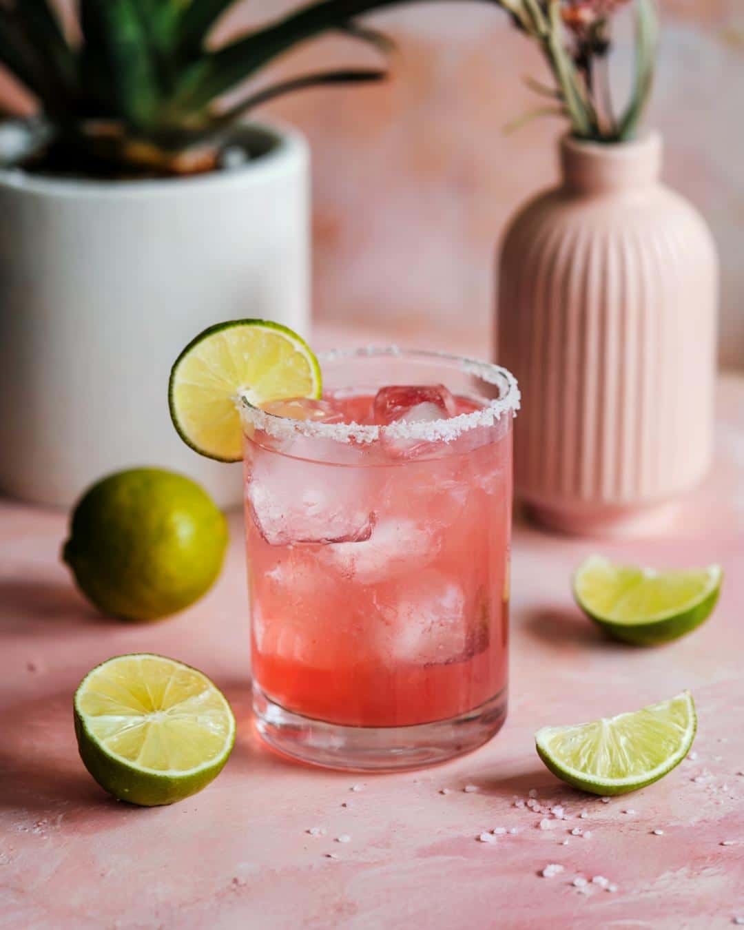 A fresh watermelon margarita in a salt-rimmed glass, highlighting how to make a pink cocktail with lime and watermelon juice.